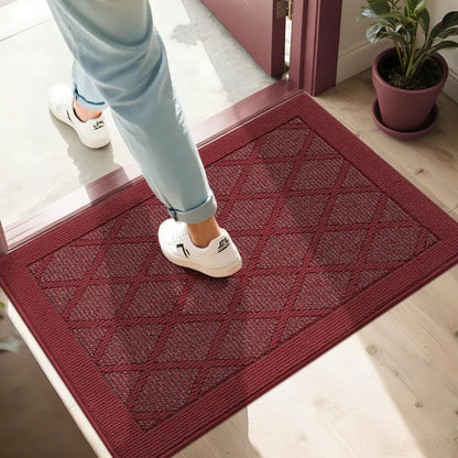 Person stepping onto a red doormat with a patterned design.
