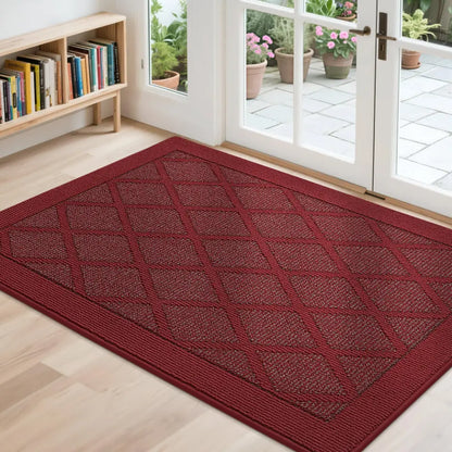 Red doormat with diamond pattern on a wooden floor, leading to a glass door with outdoor view.