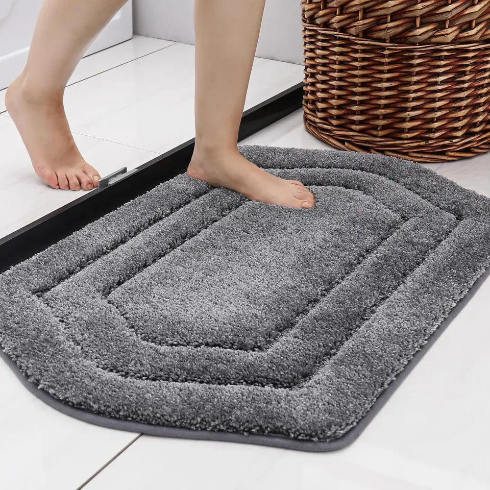 Grey bath mat with feet stepping onto it on a floor.