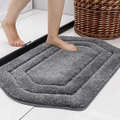 Grey bath mat with feet stepping onto it on a floor.