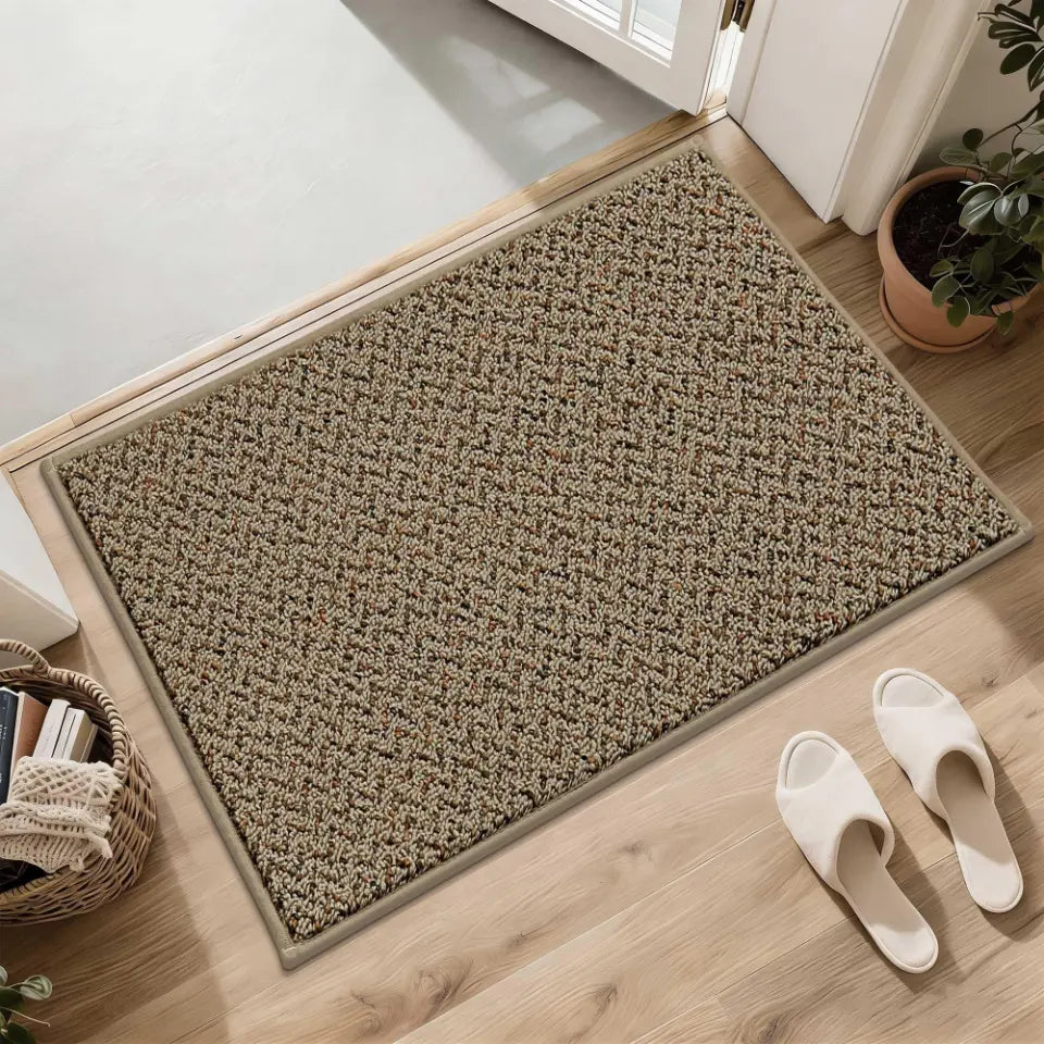 Beige doormat on a wooden floor with white slippers and a plant in the background
