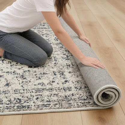 Person unrolling a patterned rug on a wooden floor
