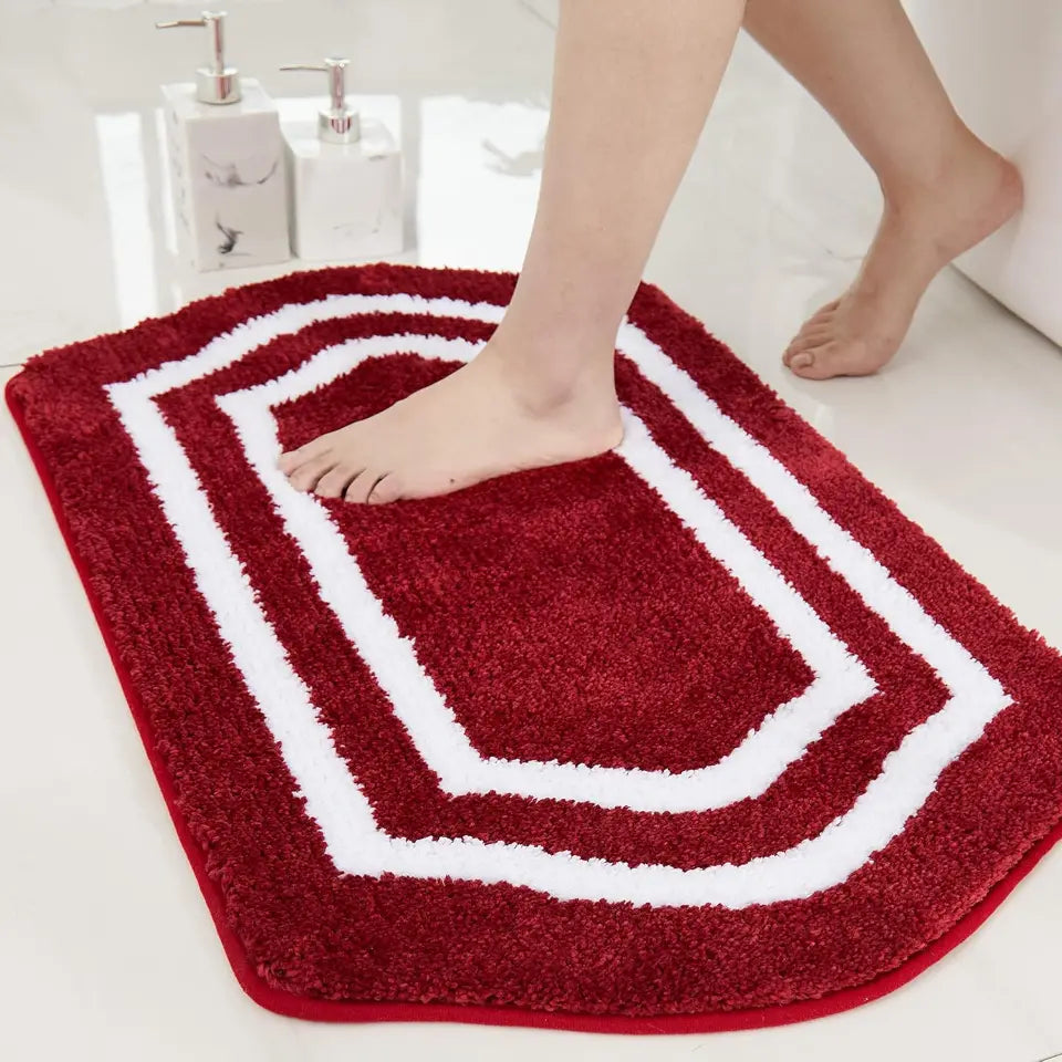 Red and white bath mat with a foot stepping onto it in a bathroom setting.