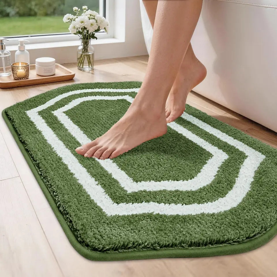Person stepping onto a green bath mat with a white border in a bathroom setting.
